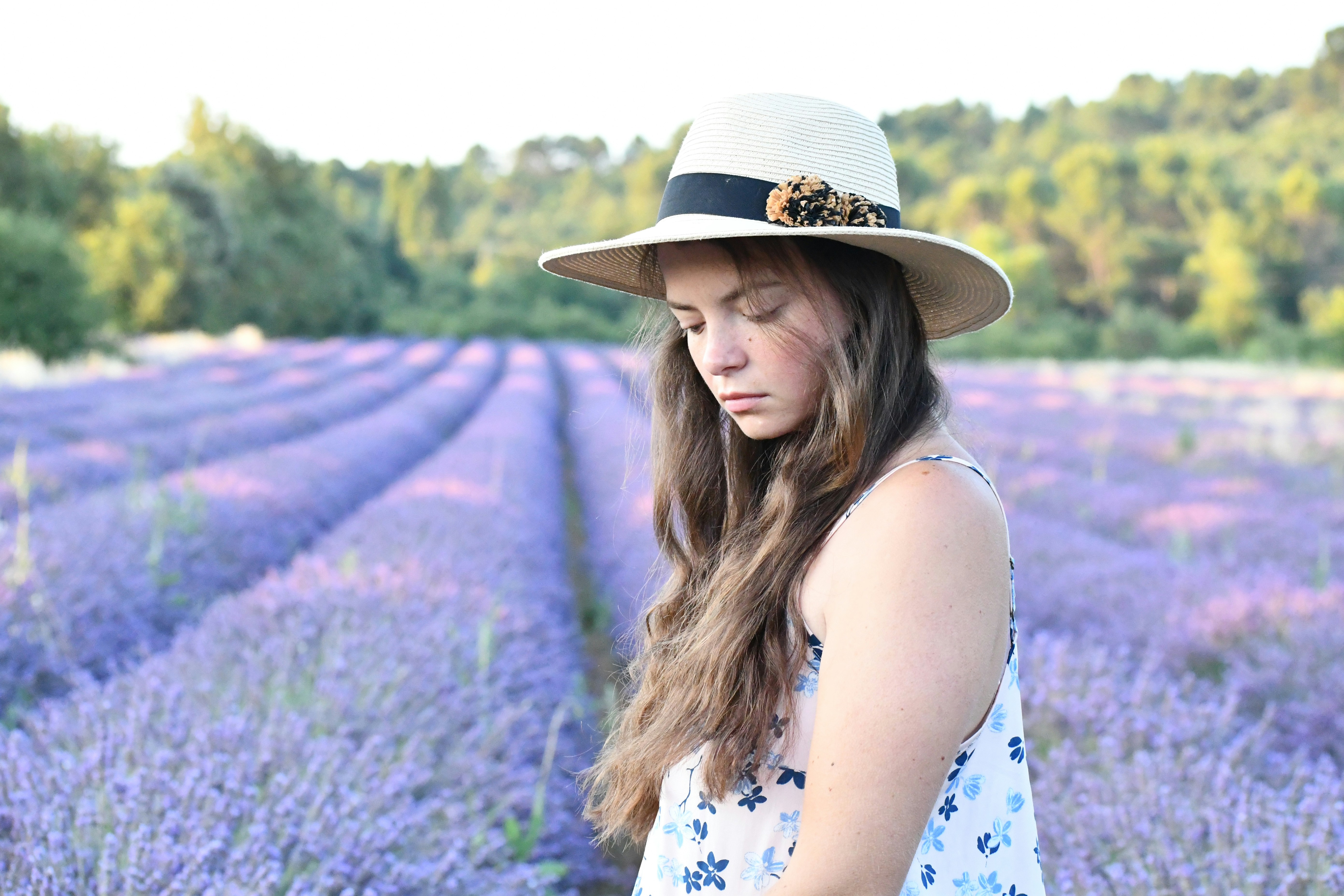 woman in black and yellow floral tank top wearing brown hat standing on green grass field