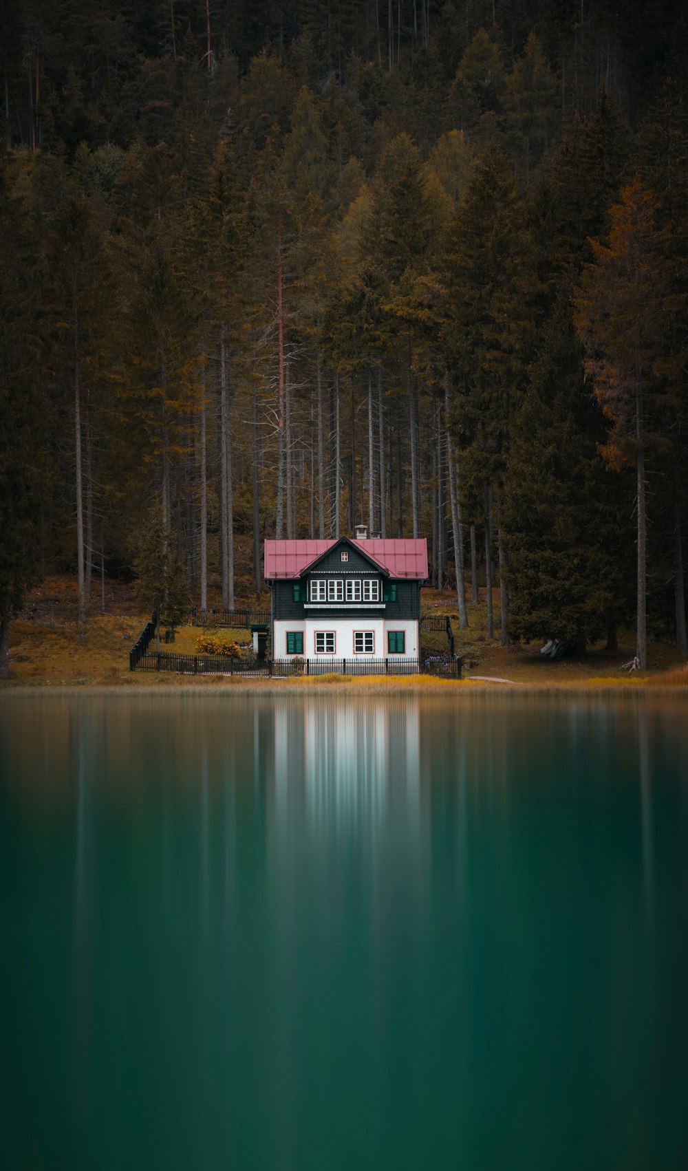 Casa bianca e marrone vicino al lago e agli alberi verdi durante il giorno