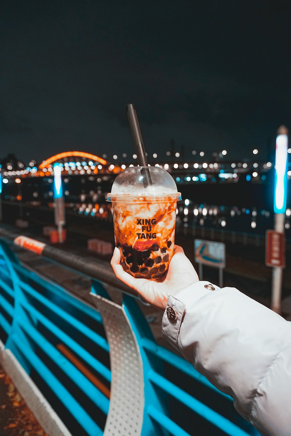 person holding clear plastic cup with brown liquid