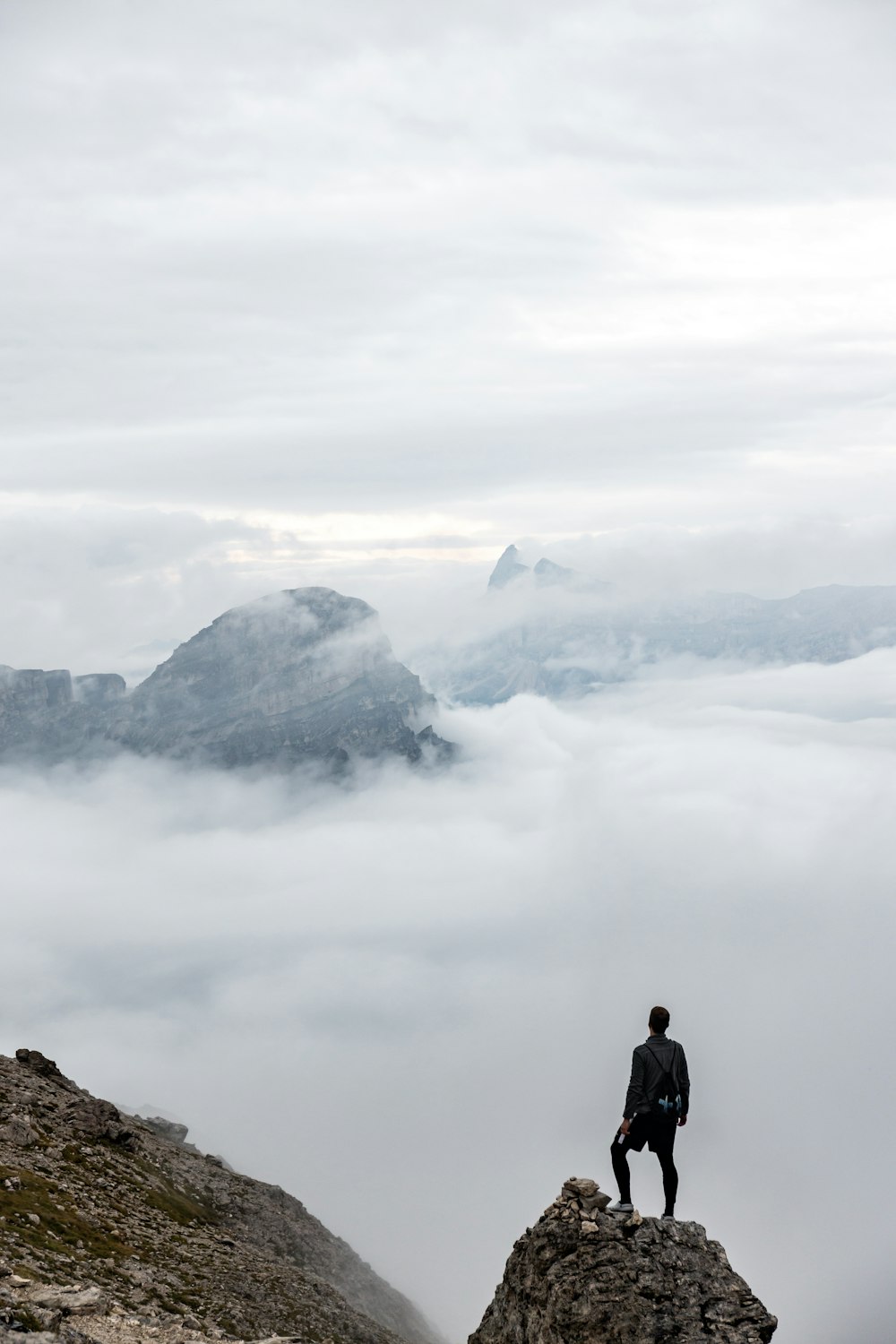 homme en veste noire debout sur la formation rocheuse pendant la journée