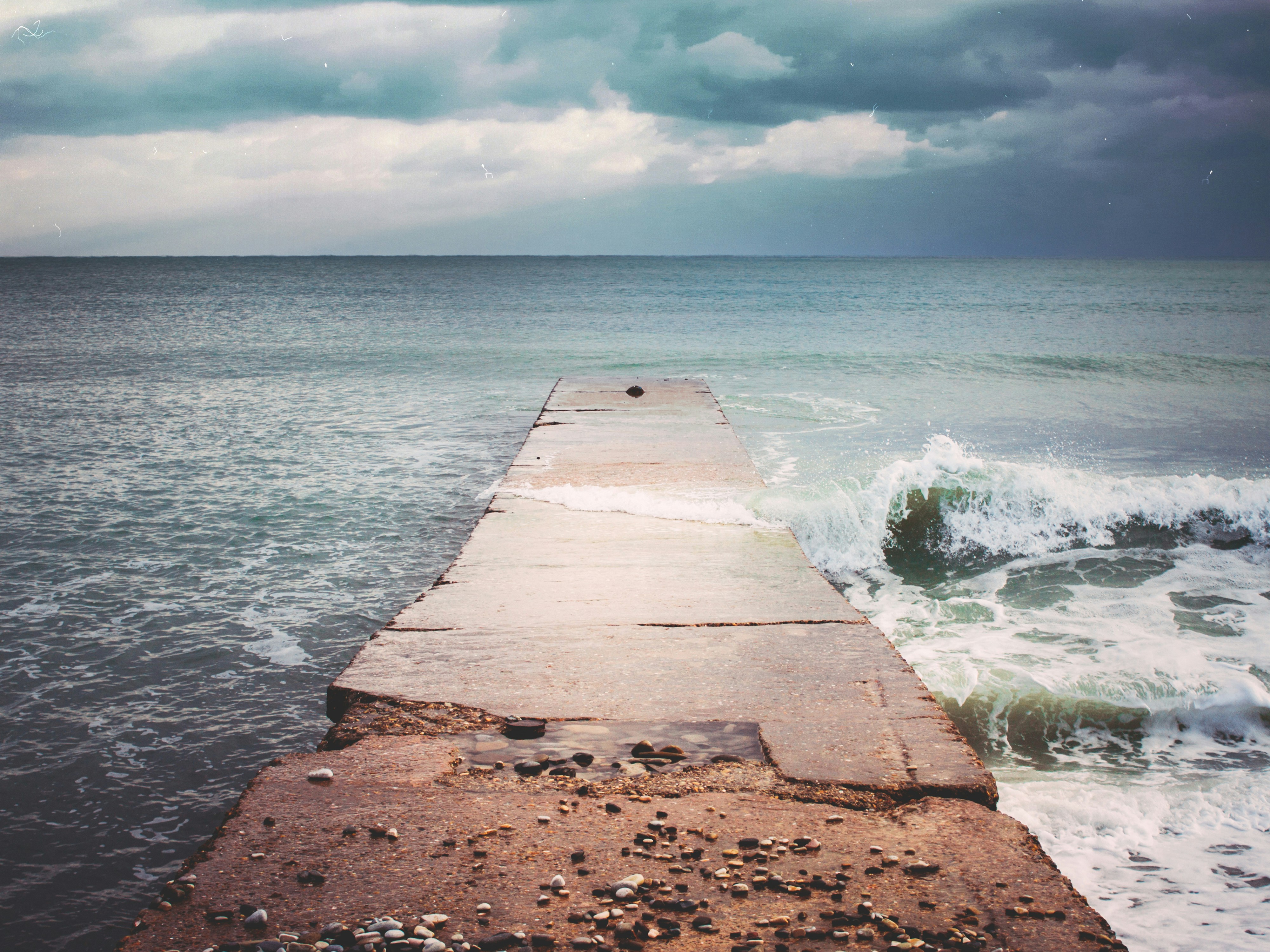 brown concrete dock on sea under blue sky during daytime