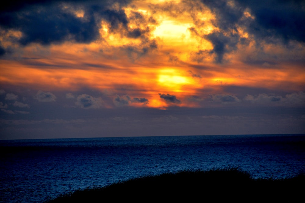 body of water under cloudy sky during sunset