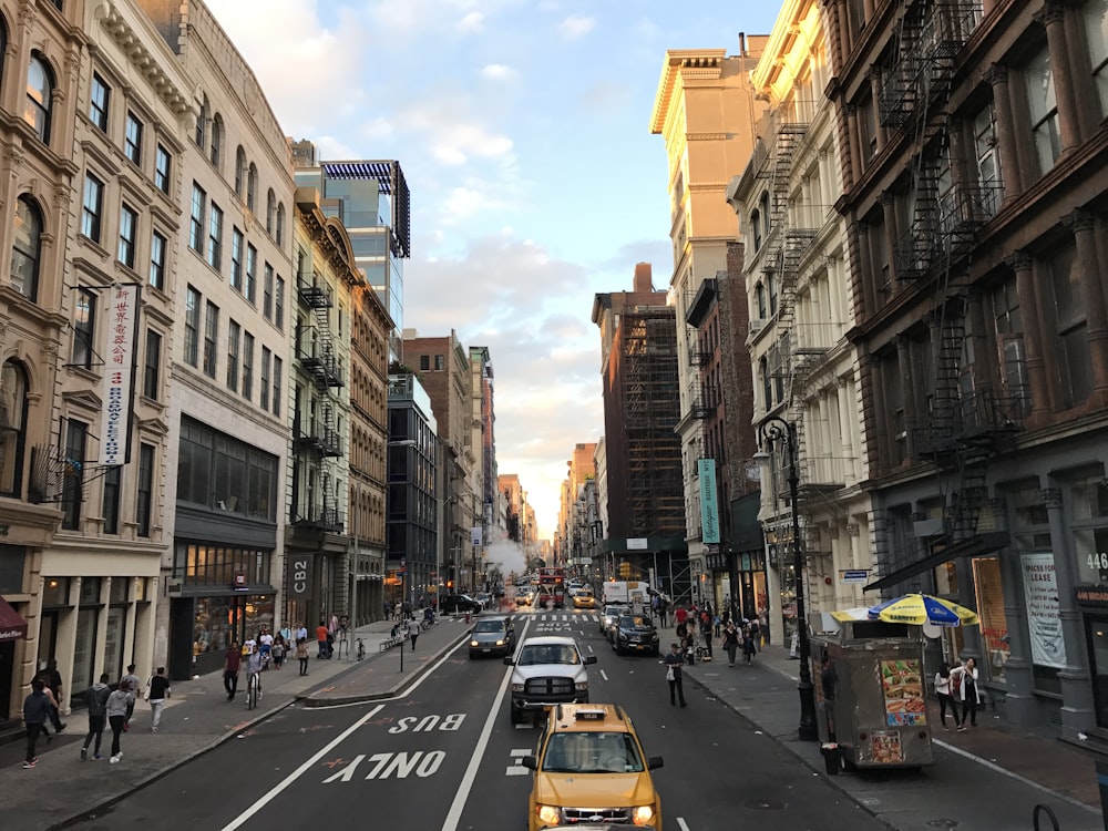 cars on road between high rise buildings during daytime