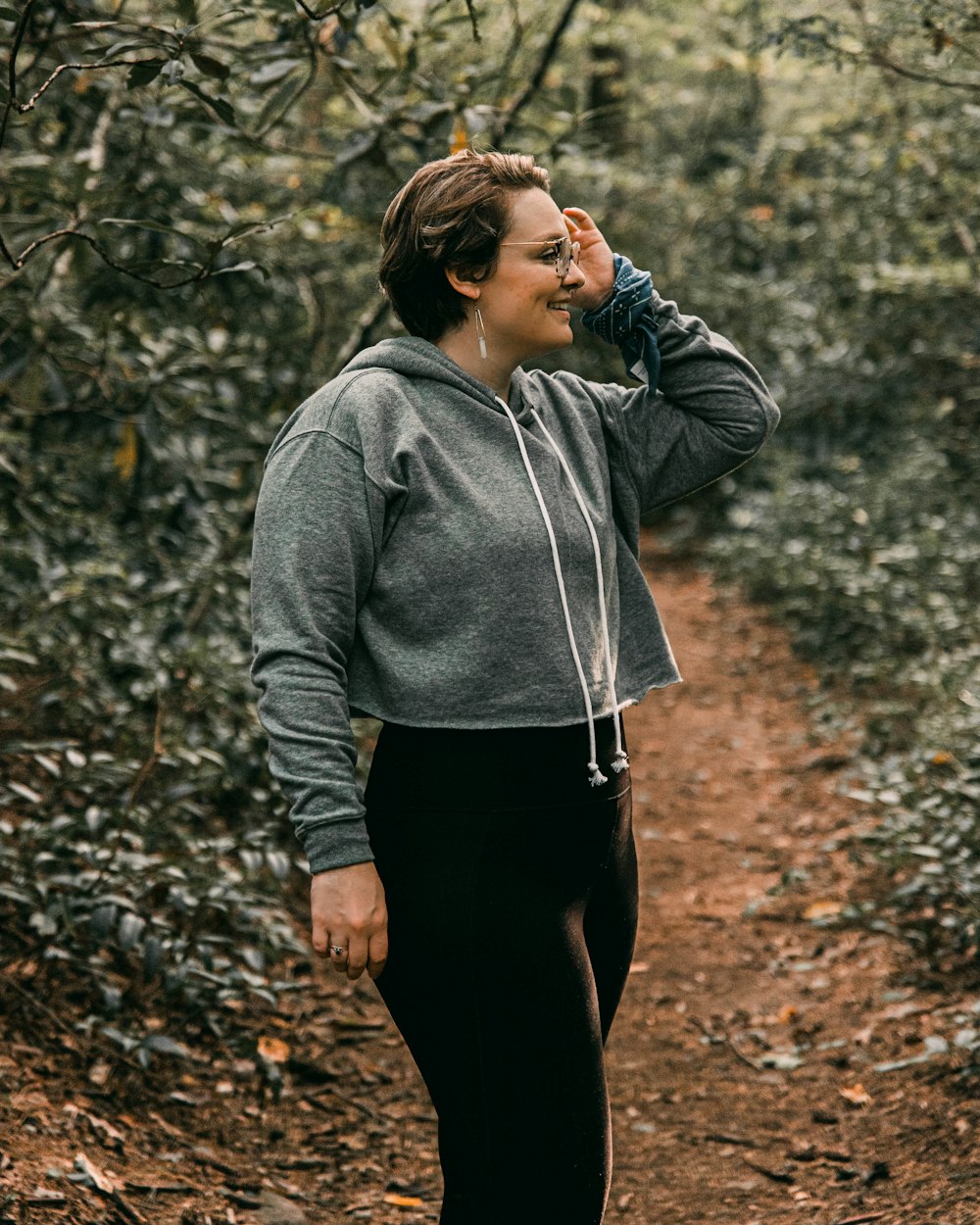 woman in gray hoodie standing on brown dried leaves during daytime