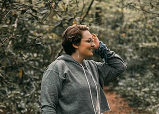 woman in gray hoodie standing on brown dried leaves during daytime