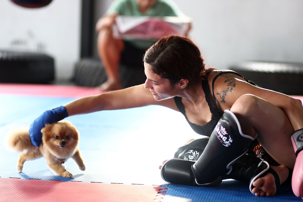 woman in black tank top and black shorts sitting on floor with brown dog