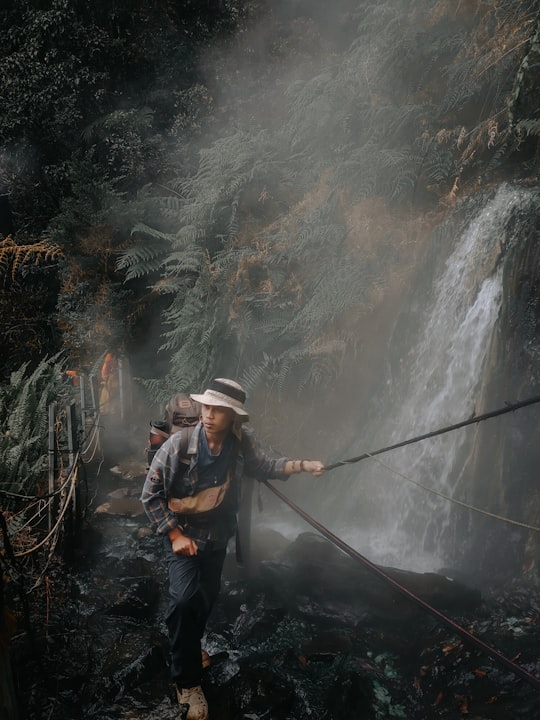 man in black jacket and brown hat holding black fishing rod in Taman Nasional Gunung Gede Pangrango Indonesia