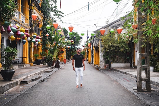 woman in black t-shirt and white pants walking on street during daytime in Hoi An Vietnam
