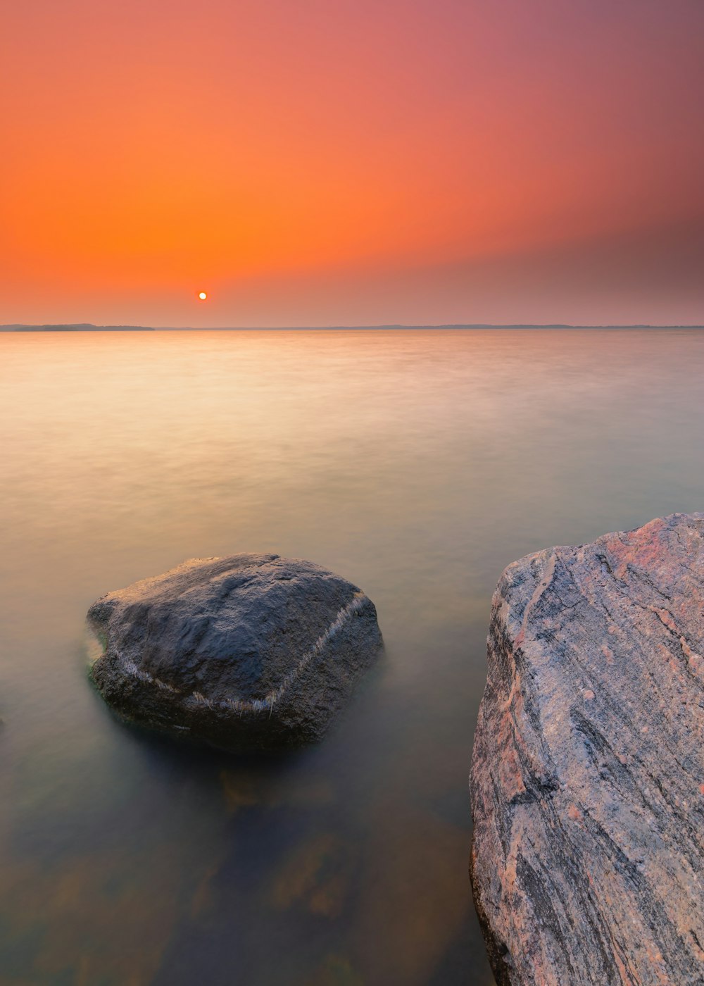Formación de rocas grises en el cuerpo de agua durante la puesta del sol