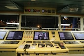 Close-up of advanced maritime navigation equipment glowing with data on a ship bridge.