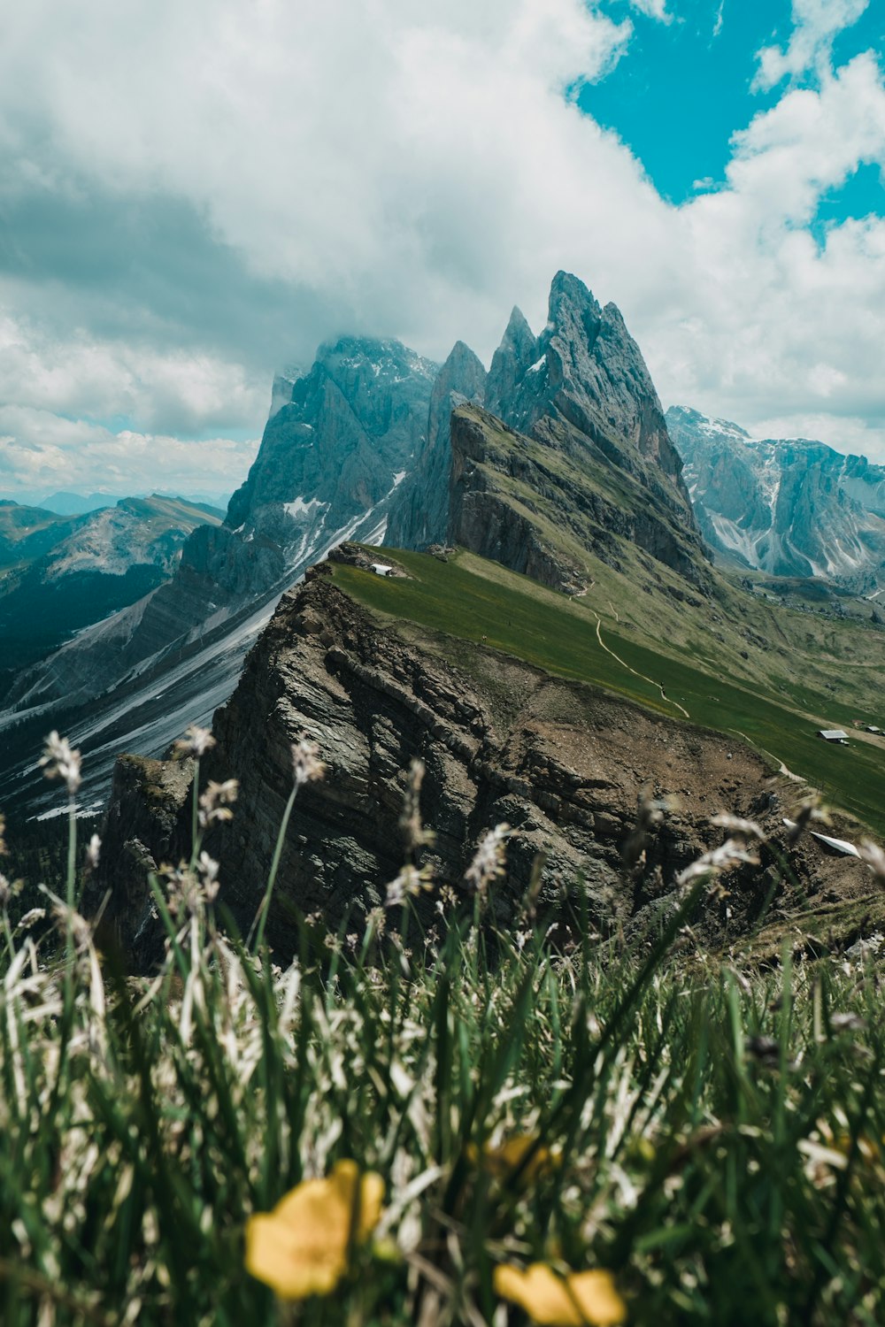 green grass field near mountain under white clouds during daytime