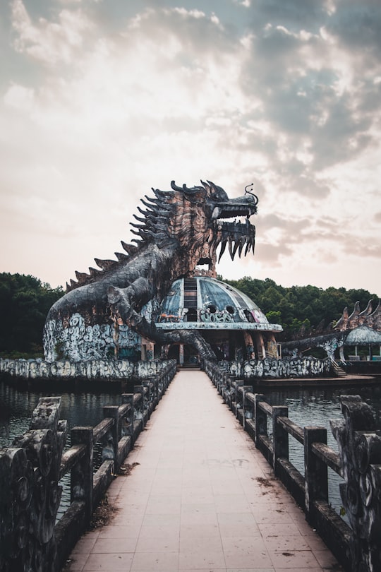 brown dragon statue near body of water during daytime in Thuy Tien lake Abandoned Water Park Vietnam