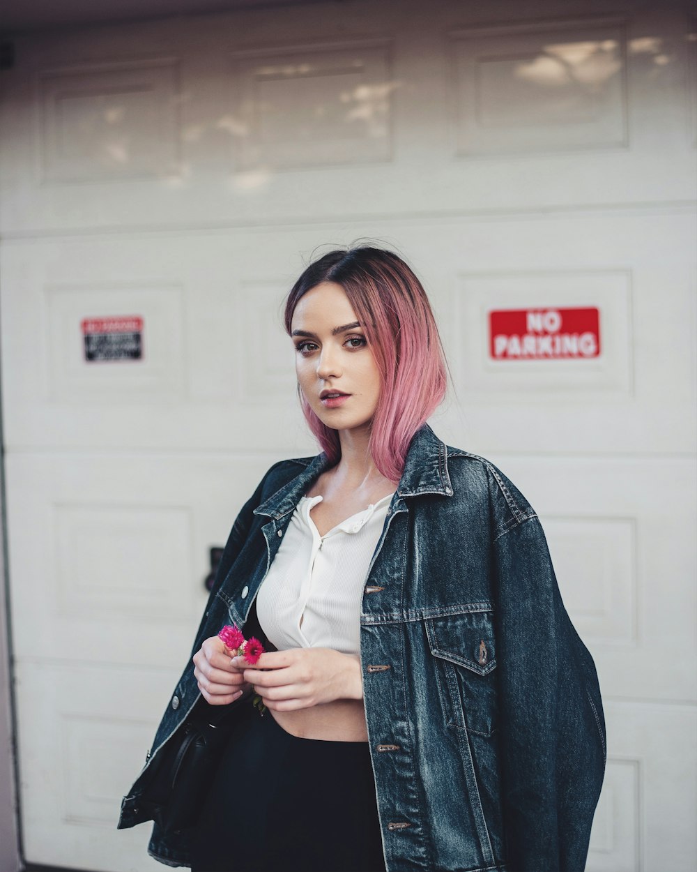 woman in blue denim jacket standing near white wall