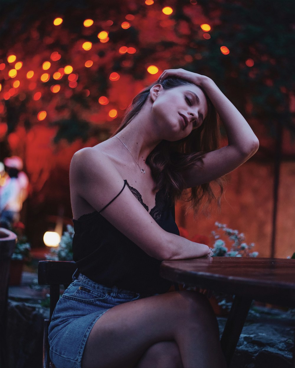 woman in black tank top and blue denim shorts sitting on brown wooden chair