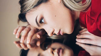 woman in red long sleeve shirt holding her face