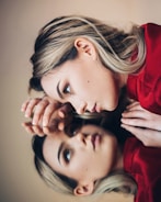 woman in red long sleeve shirt holding her face