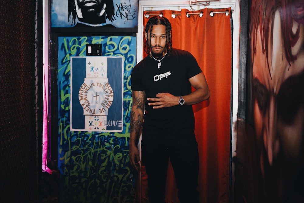 man in black crew neck t-shirt standing beside red curtain