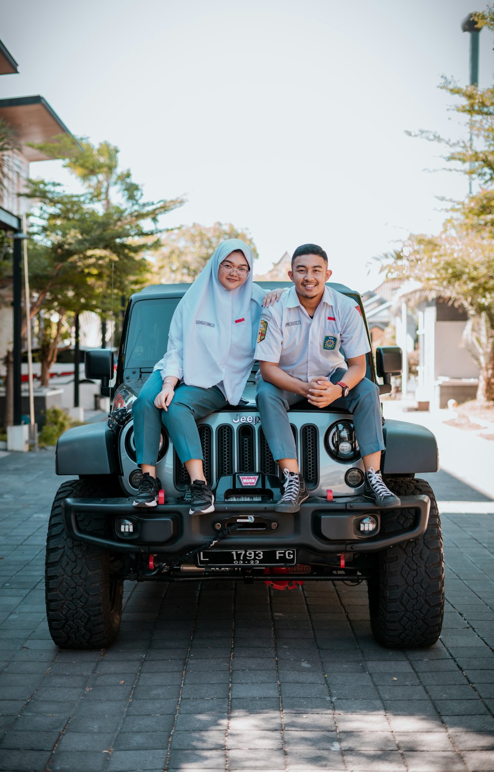 2 women and man sitting on black jeep wrangler