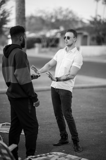 man in white dress shirt and black pants standing beside man in black long sleeve shirt