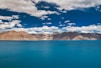 blue sea near brown and white mountains under blue sky during daytime