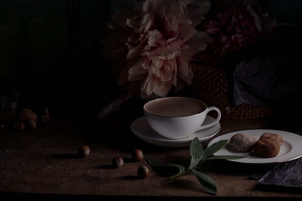 white ceramic teacup on saucer beside pink flower