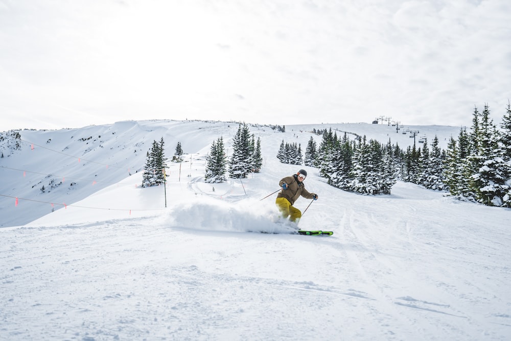 woman in white jacket and brown pants sitting on snow covered ground during daytime