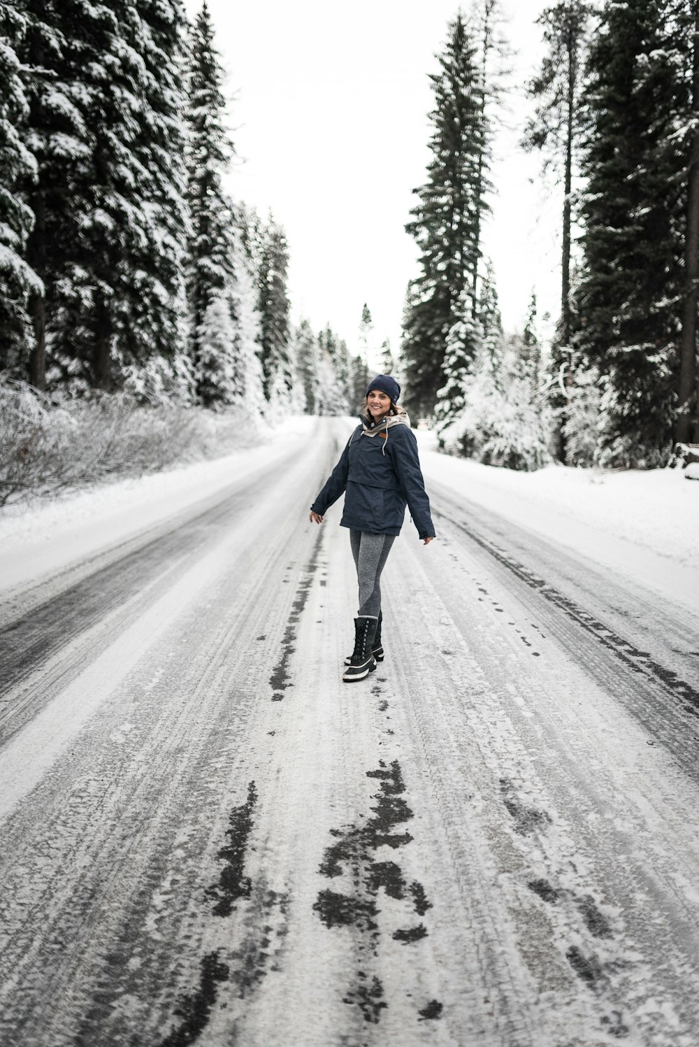 Frau im blauen Kittel geht tagsüber auf schneebedeckter Straße spazieren