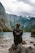 woman in black leather jacket standing on rock near body of water during daytime