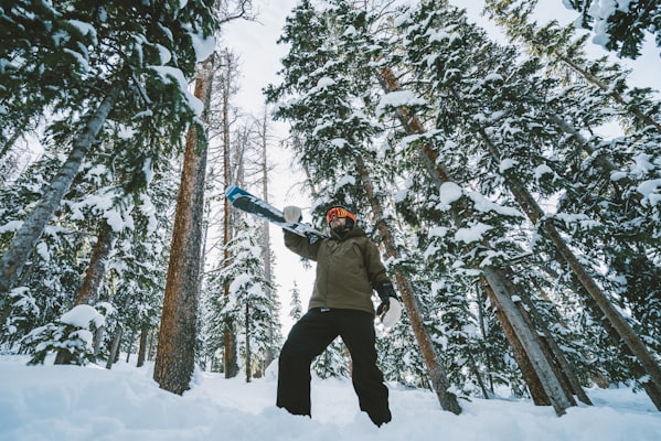 Snowboarder riding through snowy glades at Winter Park