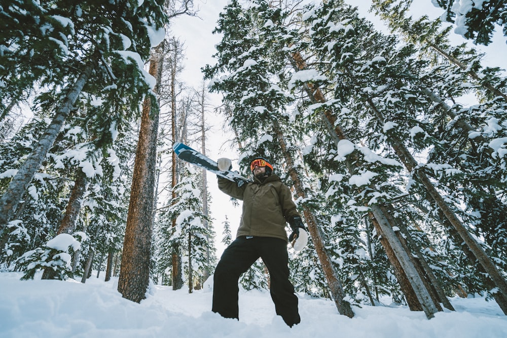 man in brown jacket and black pants playing snow board on snow covered ground during daytime