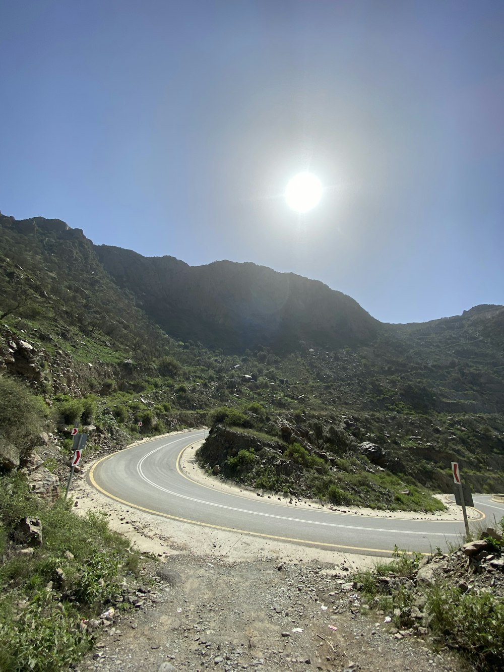 gray concrete road between green mountains during daytime