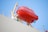 A bright orange lifeboat is securely attached to the side of a ship, hoisted on a metal frame. The background is a clear blue sky, and the ship's deck is partially visible with some safety equipment like life rings.