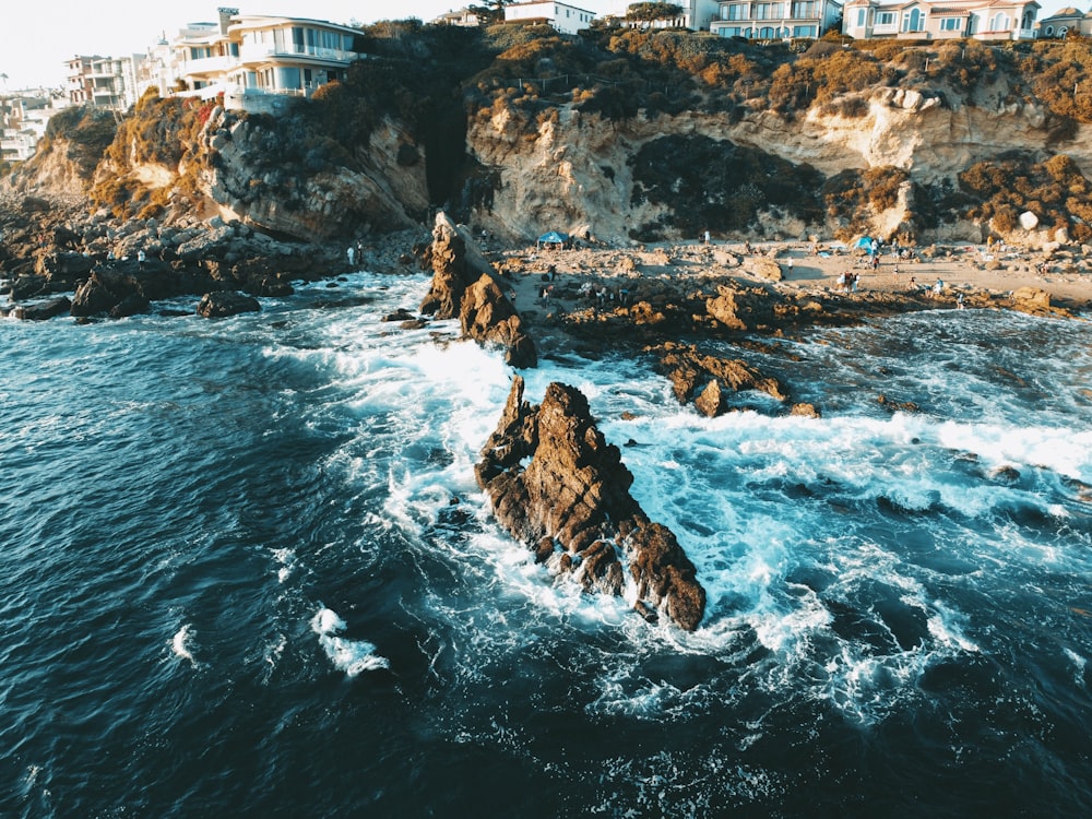 Donna in canotta nera che si siede sulla formazione rocciosa vicino al mare durante il giorno