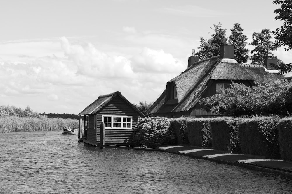 grayscale photo of house near body of water