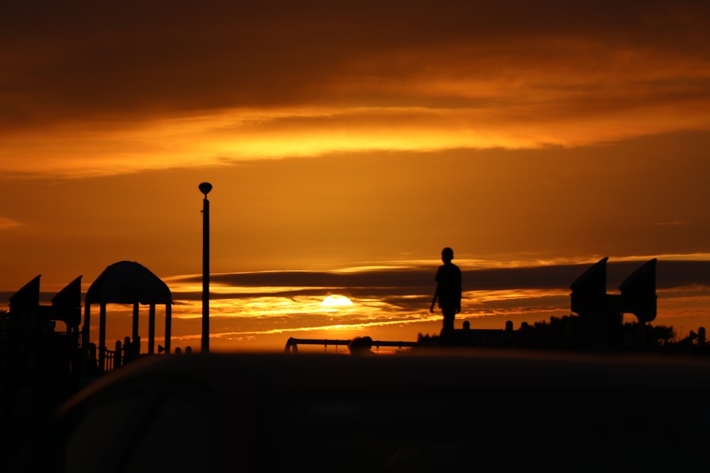 silhouette of man and woman walking on beach during sunset