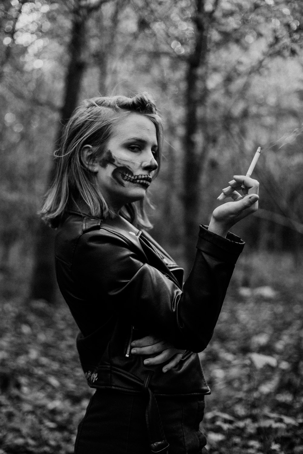 grayscale photo of woman in black leather jacket holding cigarette stick