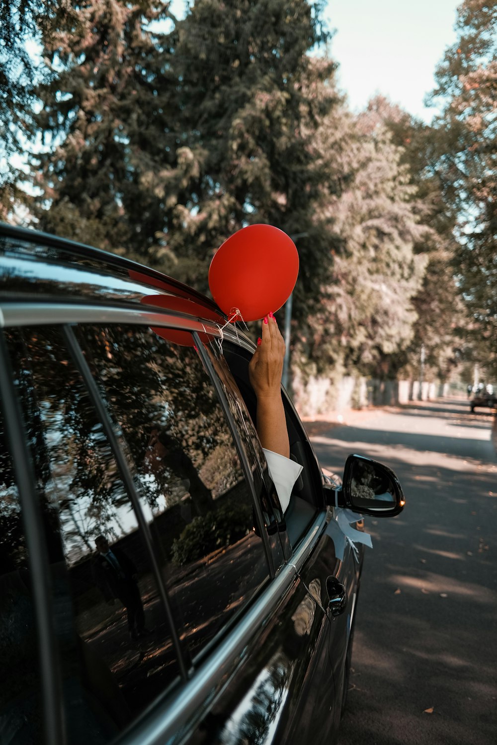 person holding red balloon in car