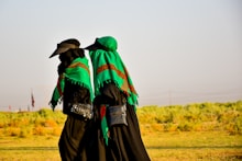 person in green hoodie and green knit cap standing on green grass field during daytime