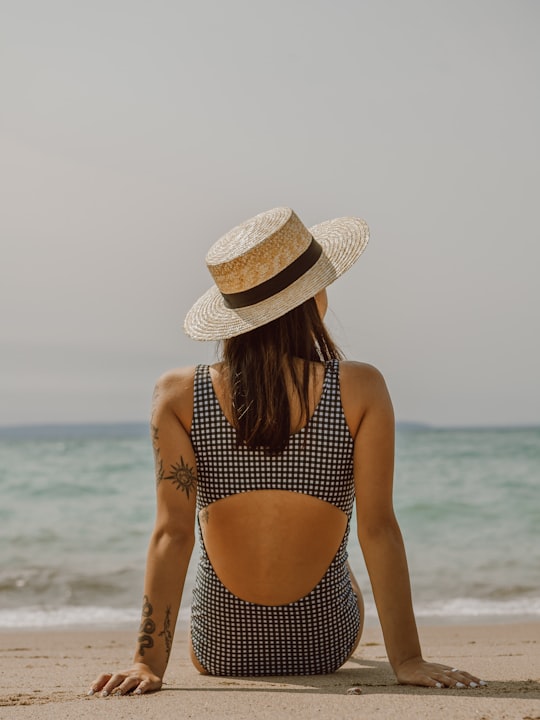 woman in black and white polka dot bikini wearing brown sun hat standing on beach during in Tiny Canada