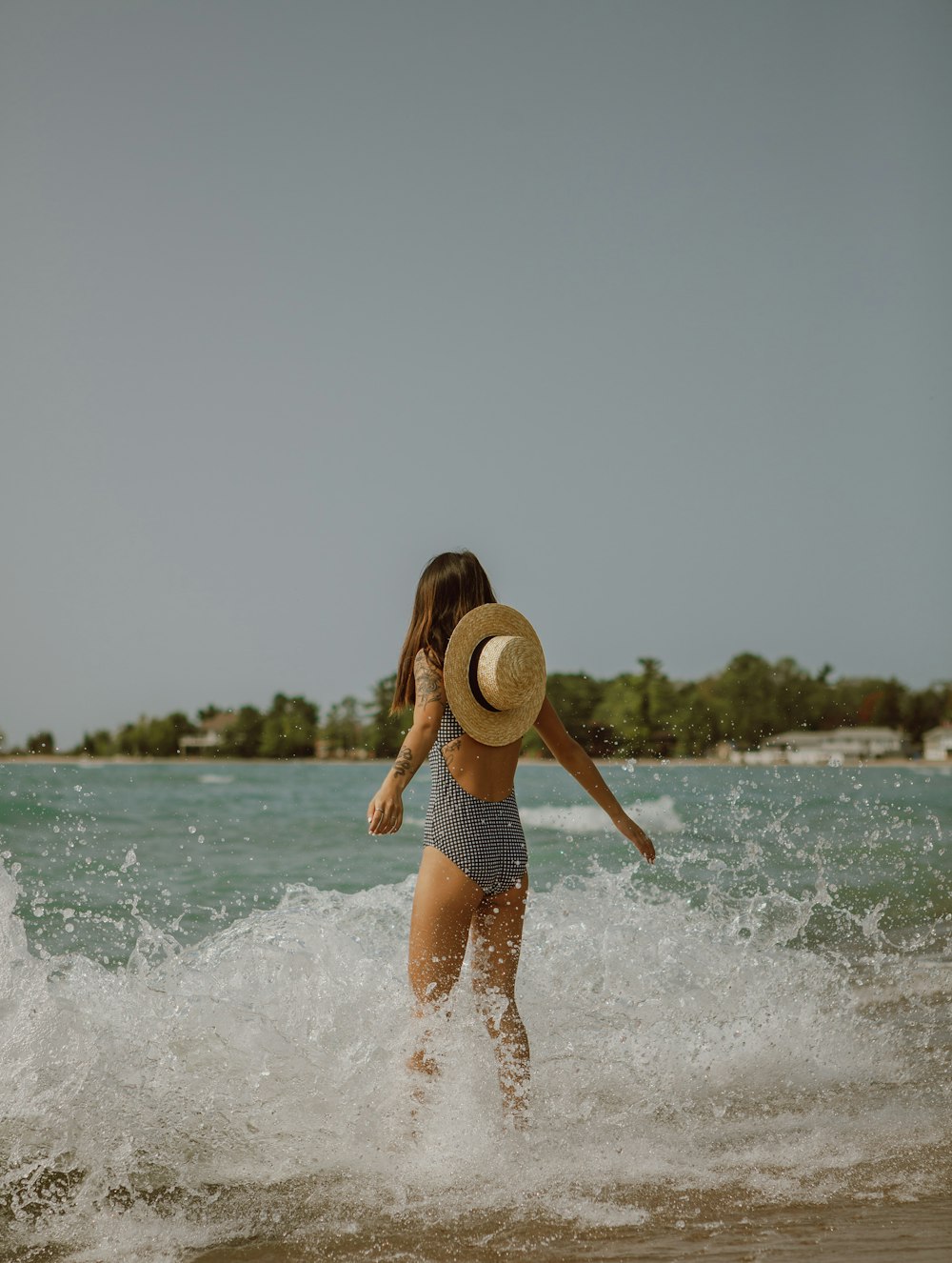 woman in blue shorts and white hat running on beach during daytime