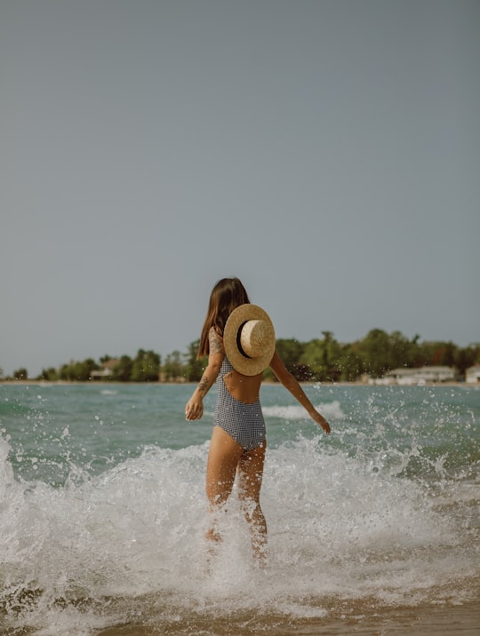 woman in blue shorts and white hat running on beach during daytime in Tiny Canada