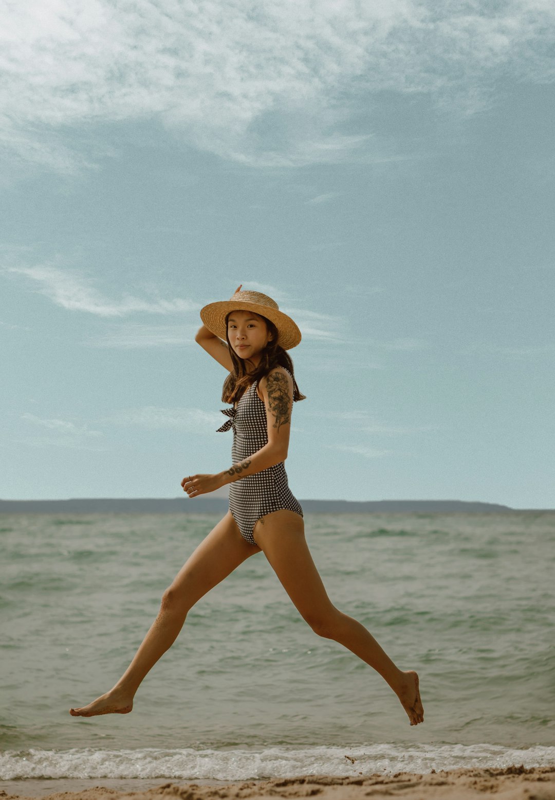 woman in white and black polka dot bikini wearing brown sun hat standing on beach during