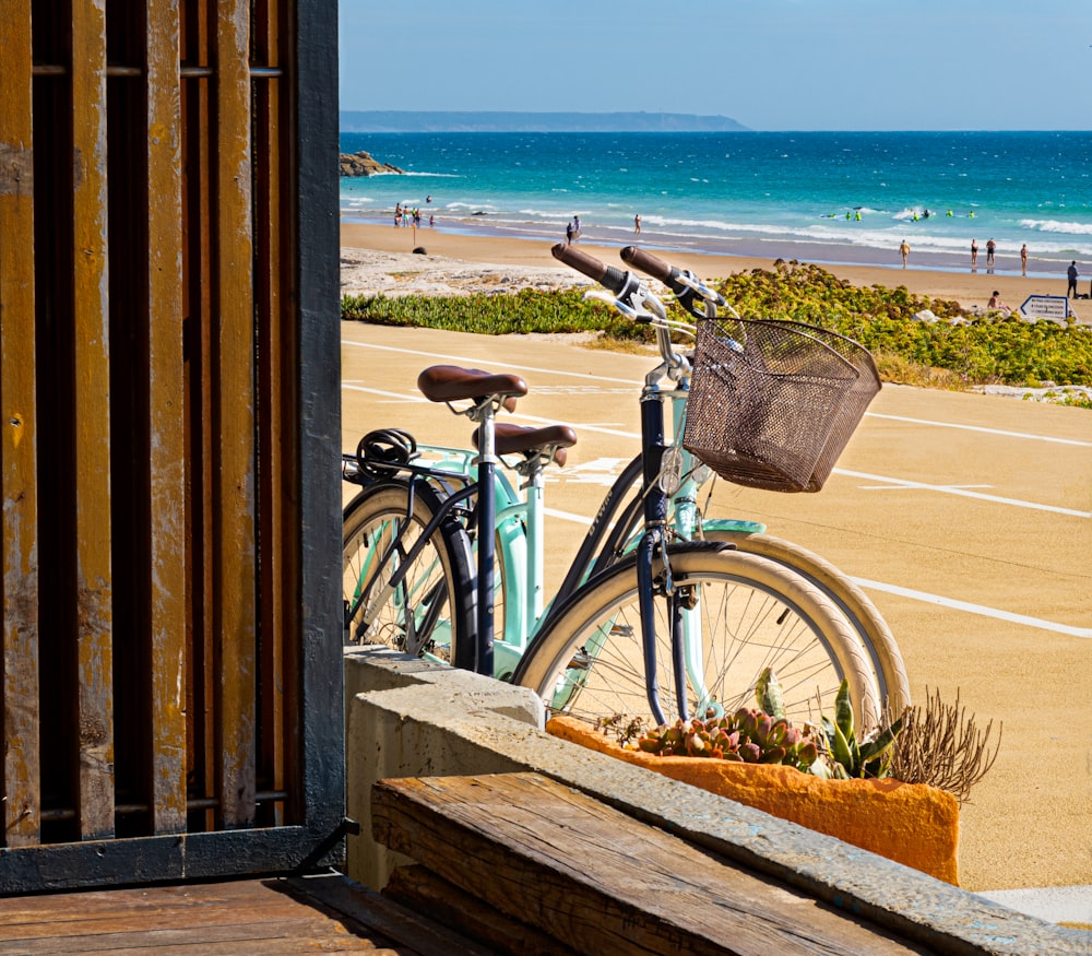 blue city bike on wooden fence near sea during daytime