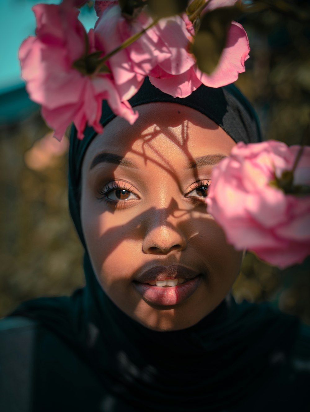 woman in black hijab with pink flower on her head