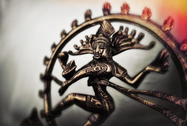 A brass sculpture of a graceful dancer, glowing warmly against a charcoal backdrop.