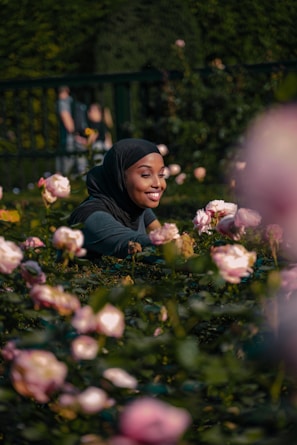 woman in black hijab holding white flowers