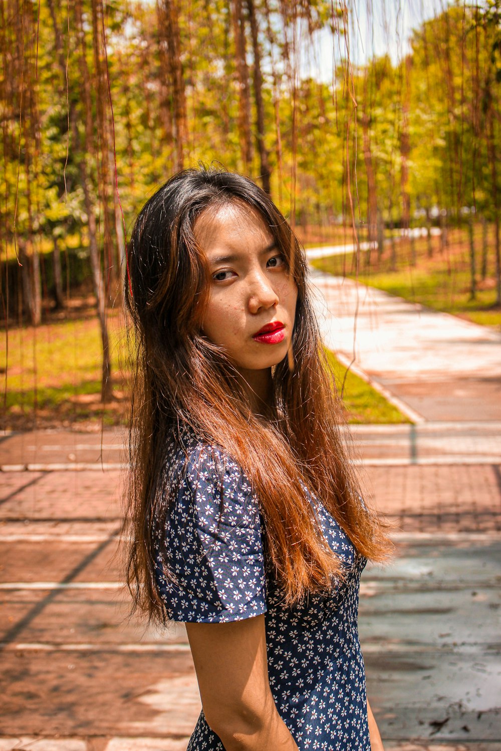 woman in black and white polka dot shirt standing on sidewalk during daytime