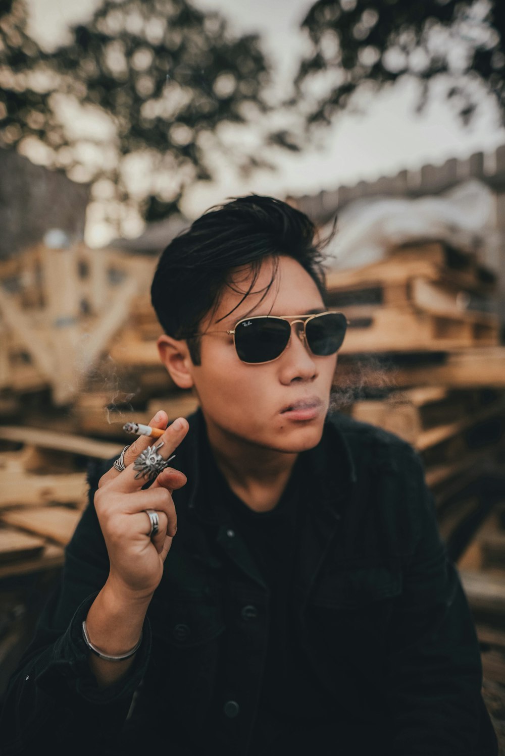 man in black sunglasses holding cigarette stick