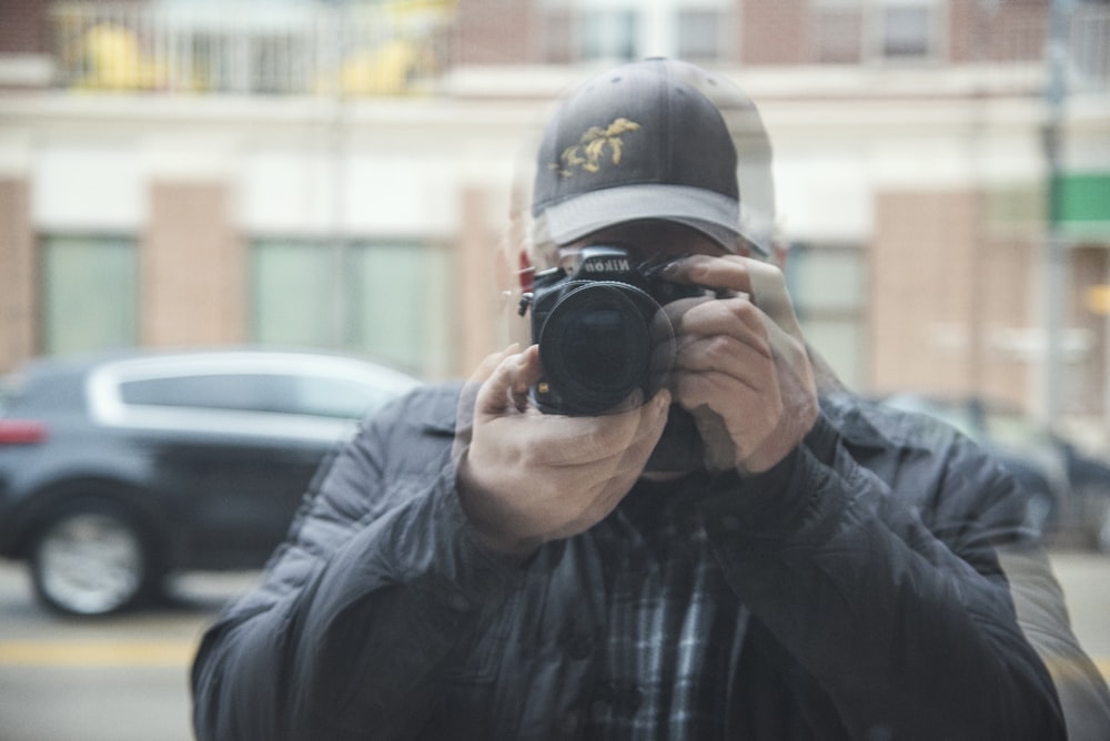 man in black leather jacket holding black dslr camera