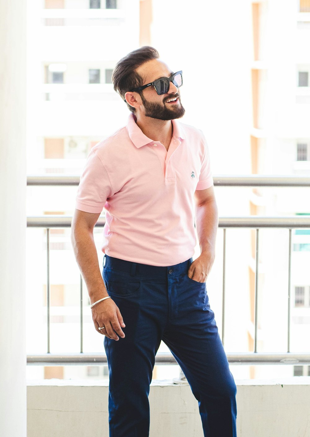 man in pink dress shirt and blue denim jeans wearing black sunglasses